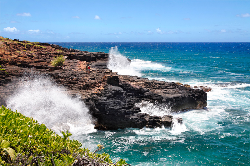 waves crash on cliffs at Makahuena Point in Hawaii