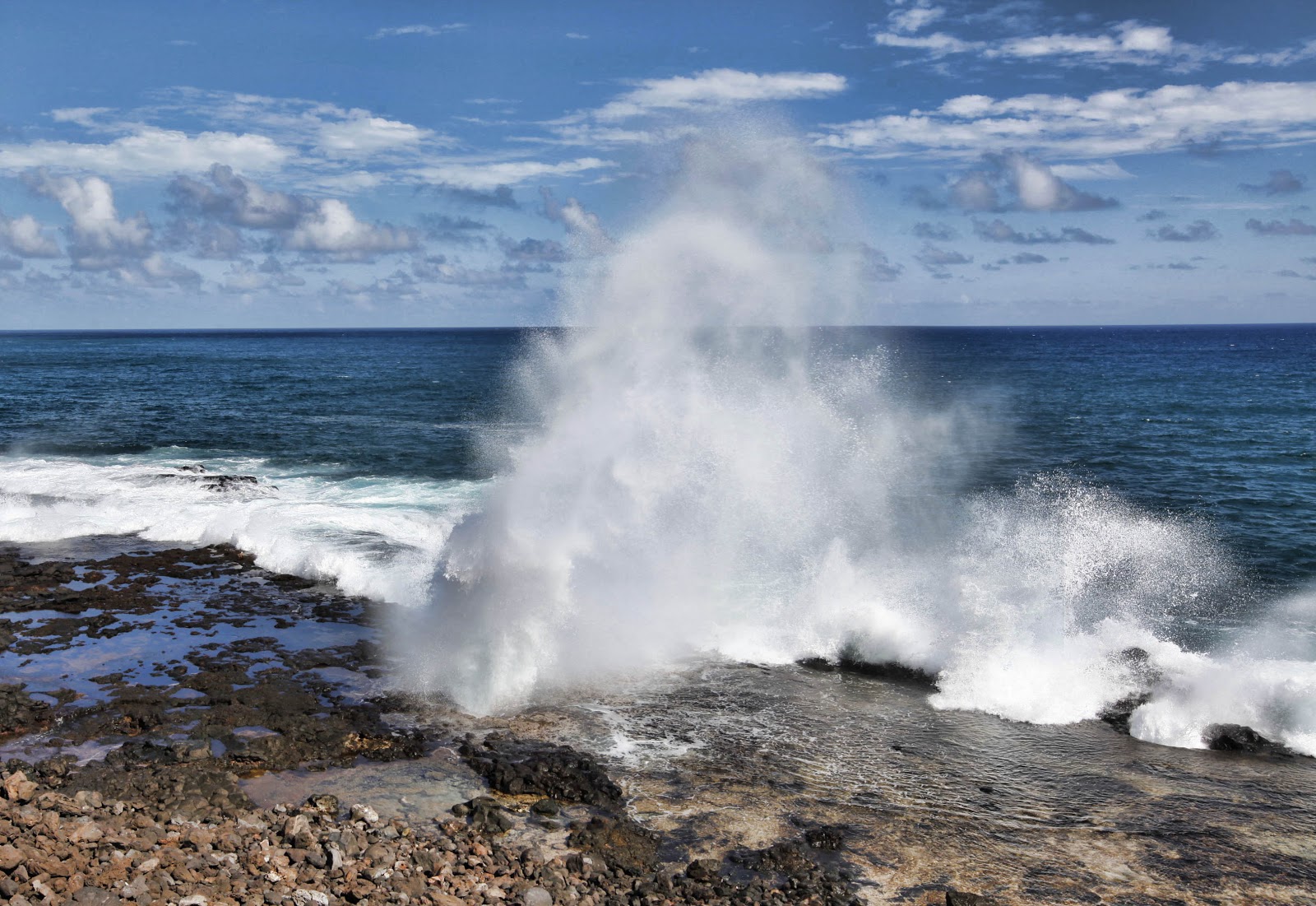 waves crash on a stony beach a spouting horn