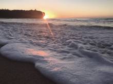 the sun rises over the pacific ocean at shipwreck's beach in kauai
