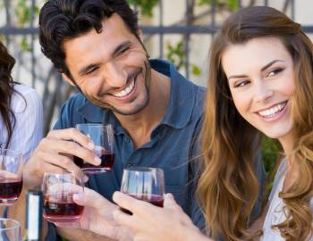 a man and a woman smile while sipping drinks at a poipu restaurant