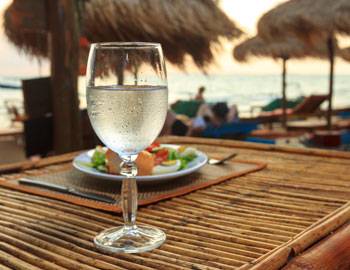 a stemmed glass of white wine stands on a bamboo table at a poipu restaurant