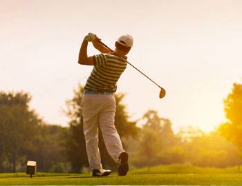 a golfer in khakis and striped polo watches his drive from a tee box in kauai